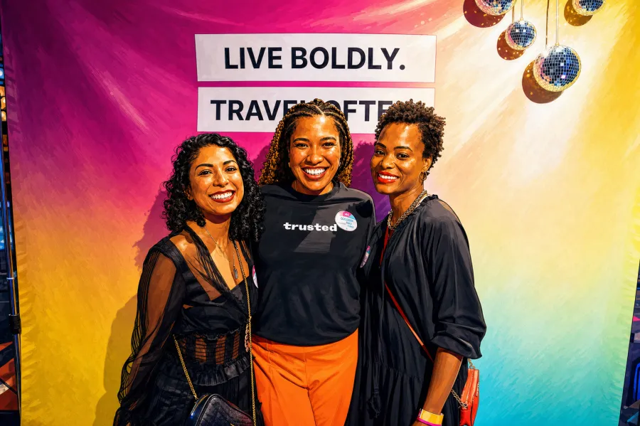 Three Trusted teammates at a company event in front of a "Live boldly. Travel often." backdrop