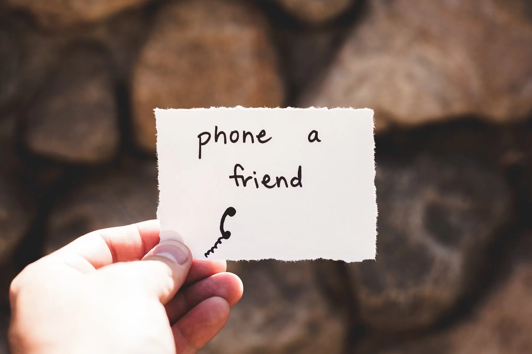hand holding piece of paper says phone a friend nursing ptsd