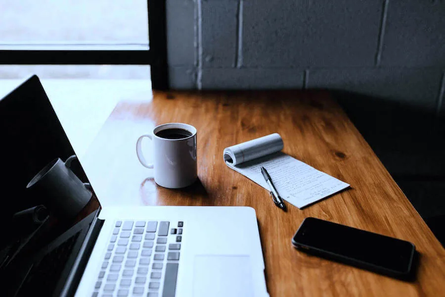laptop on desk next to coffee notepad and phone remote nursing jobs from home