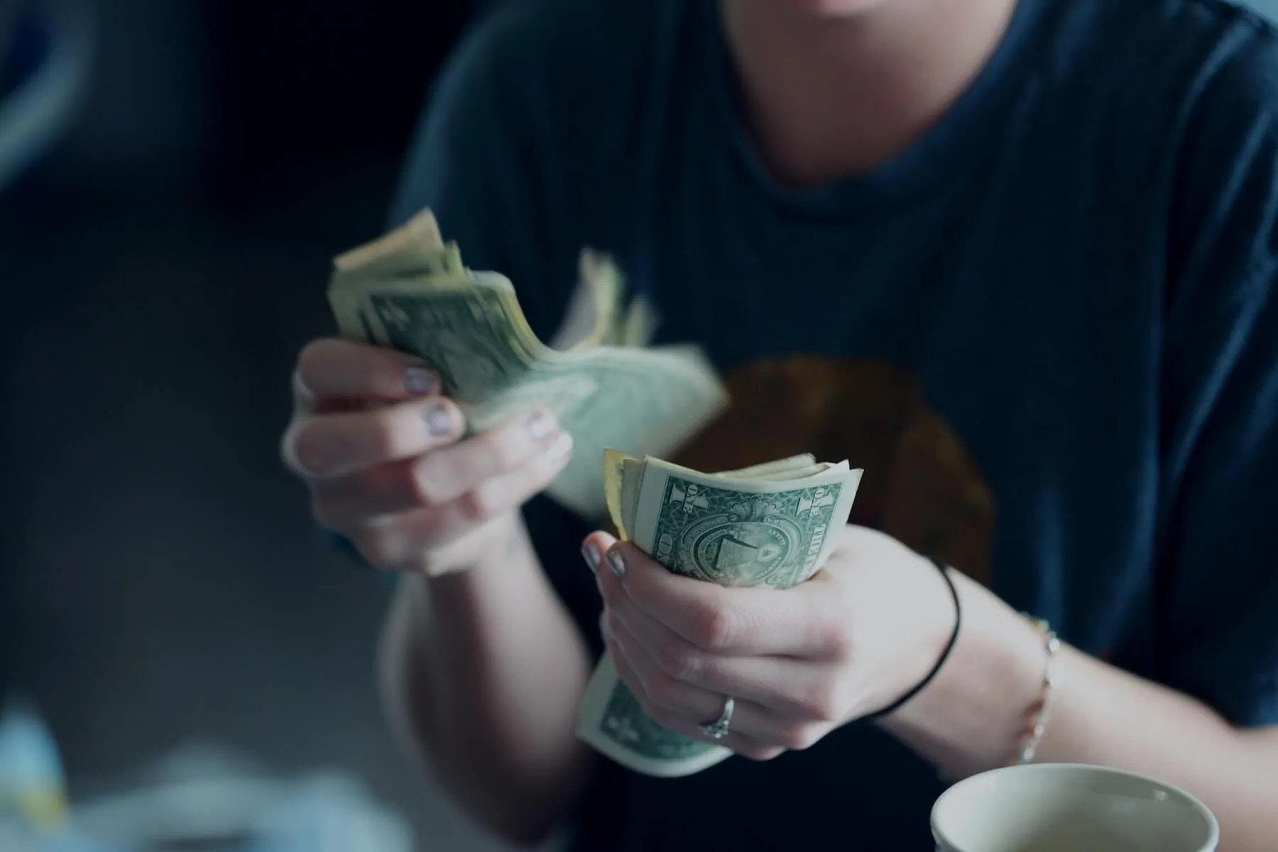 woman holding dollars in hand nursing pay decrease nursing during covid19