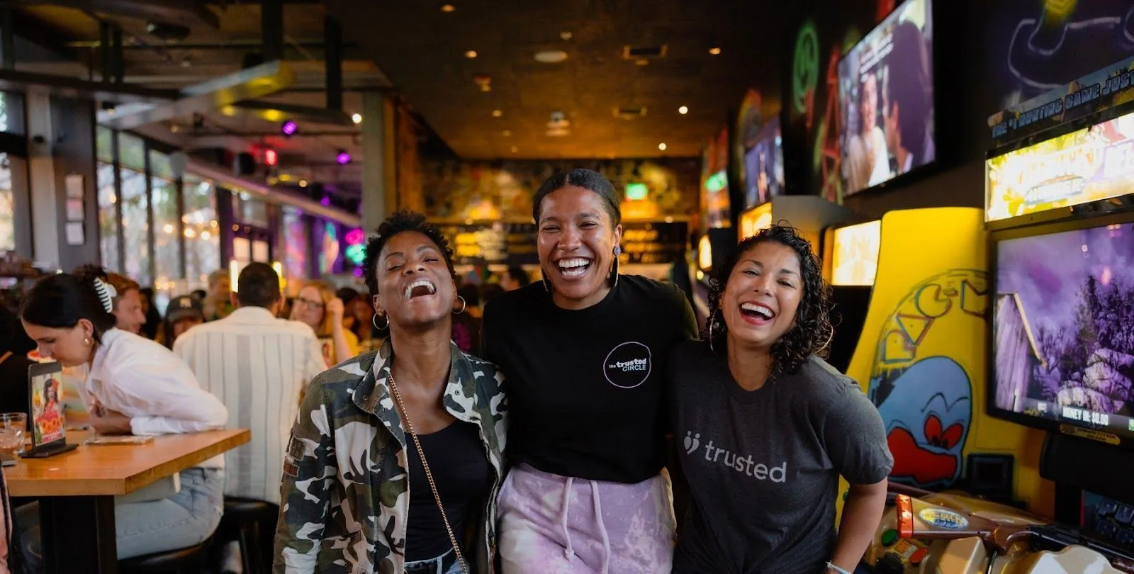 Britt, with her arms around two cheerful clinicians, all sharing a joyful moment, exemplifying the friendly and uplifting spirit of Trusted Community events.
