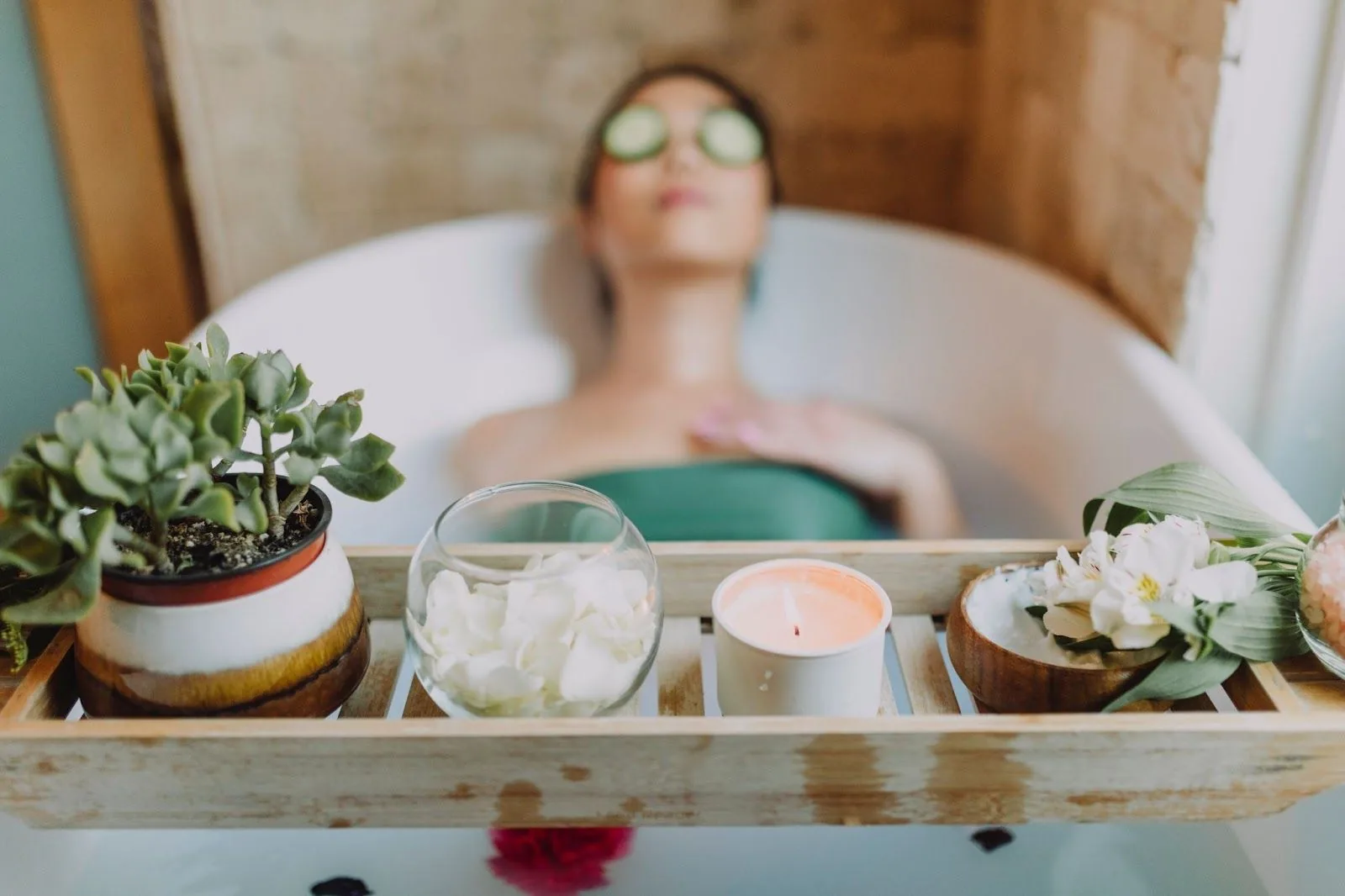 A tranquil at-home spa setting with a person relaxing in a bathtub, cucumber slices over their eyes, amidst a serene decor of candles, flowers, and a succulent plant, symbolizing self-care and stress management during the festive season.