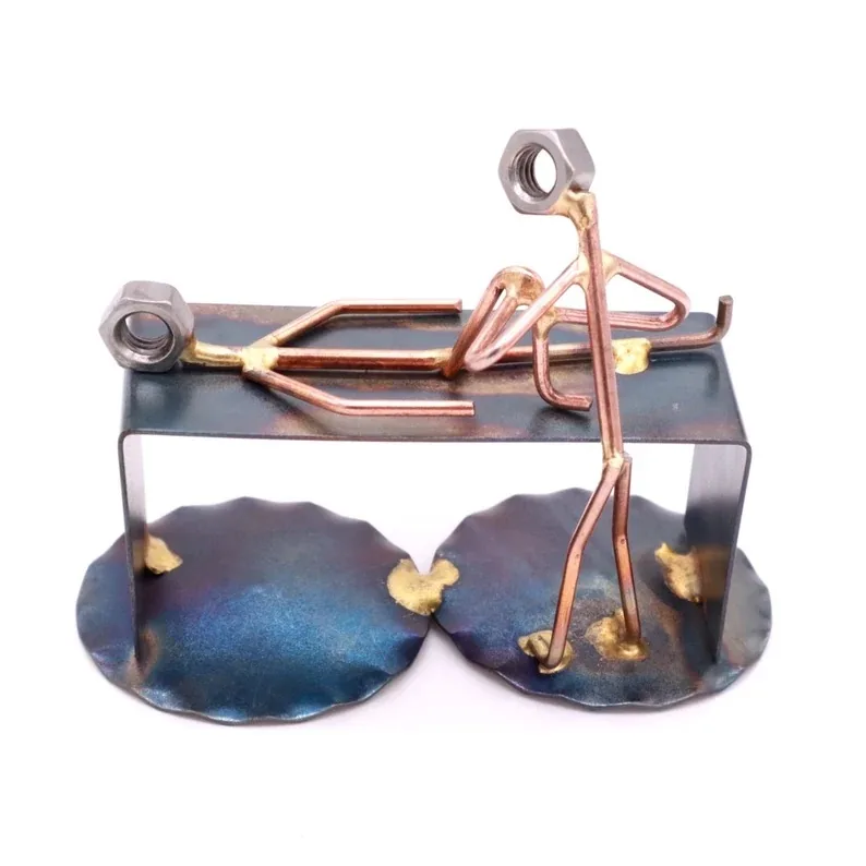 A creative and intricately assembled metal sculpture depicting a figure of a physical therapist in action, with elements crafted to represent a patient on a treatment table. The mix of copper tones and blue patina finishes gives this 4x4 inch desk sculpture a unique and personalized touch for physical therapists.
