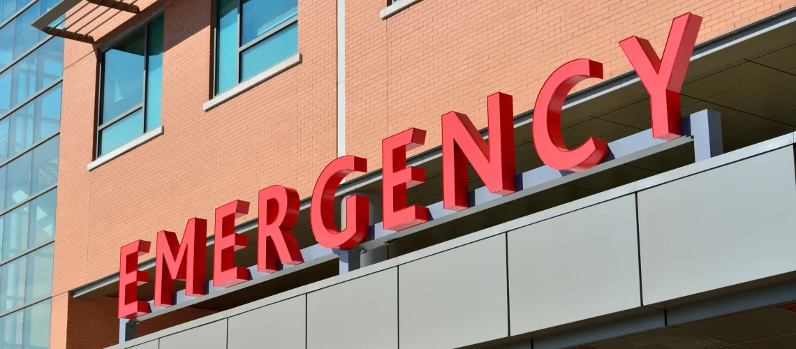 Red 'EMERGENCY' signage prominently displayed on the façade of a hospital, marking the entrance to the emergency room where urgent medical conditions are promptly addressed