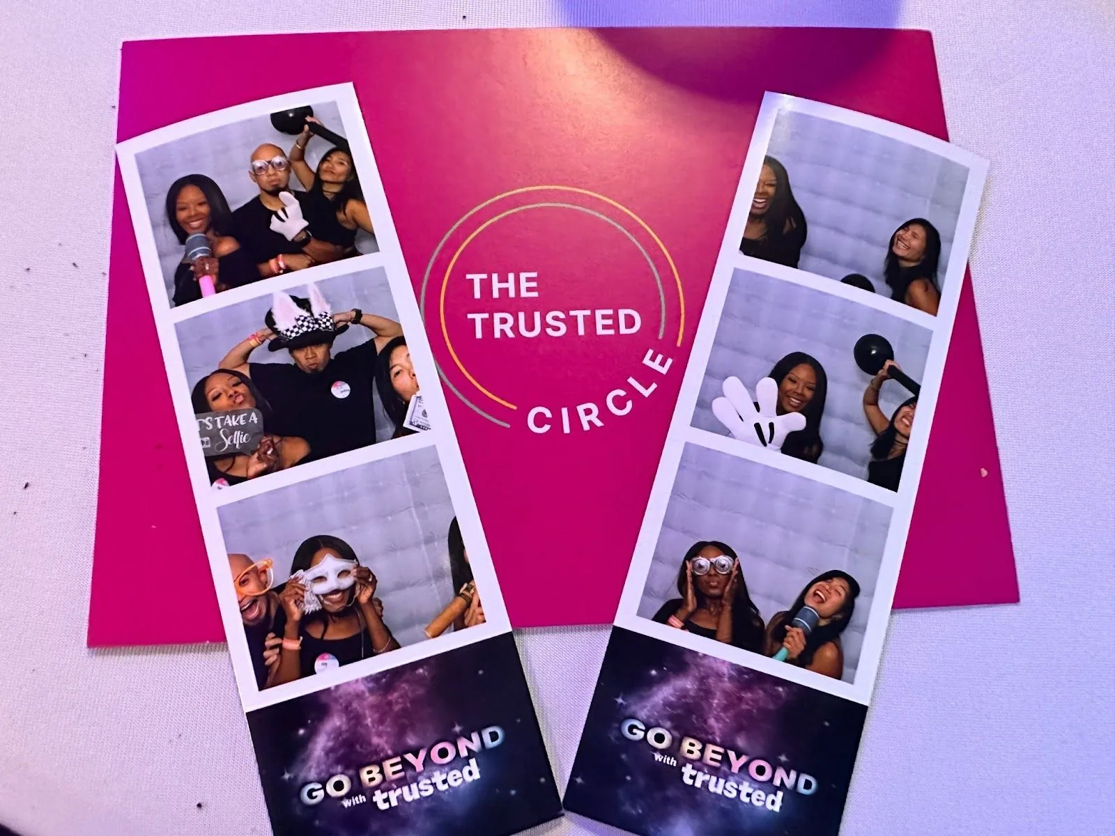 Photo booth strips showcasing laughing individuals with playful props, resting on a surface with 'THE TRUSTED CIRCLE' and 'GO BEYOND with trusted' branding, symbolizing the community's growth and excitement for the future.