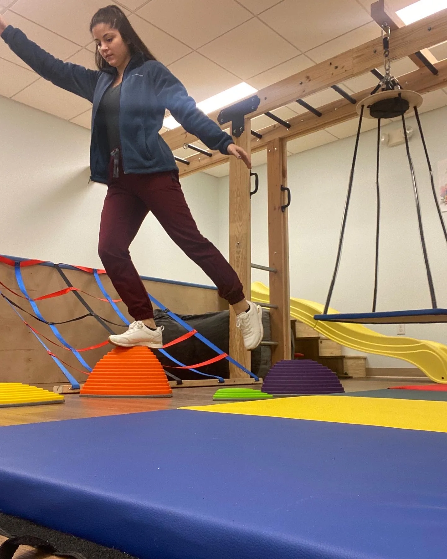 The author concentrating as she navigates stepping stones in an occupational therapy gym.